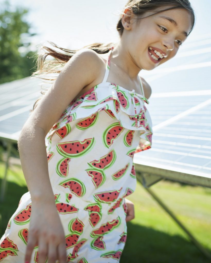 A child and her mother running beside solar panels.